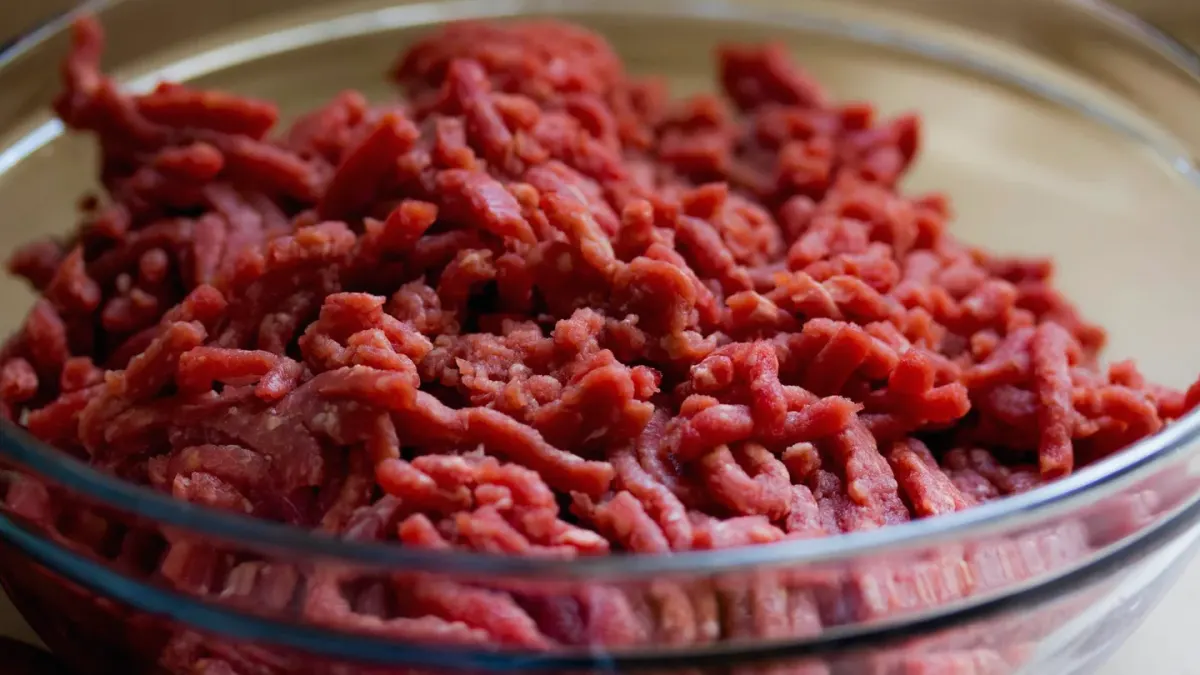 A bowl of home-cooked dog food with meat, rice, and chopped vegetables on a kitchen counter