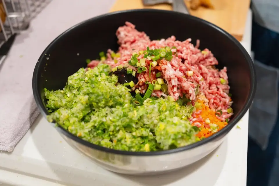 A dog eating chopped vegetables mixed into its regular food