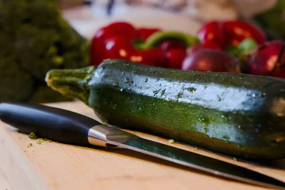 A dog sniffing chopped broccoli florets on a wooden cutting board