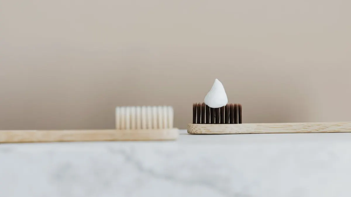 A dog toothbrush laid next to a tube of pet-safe toothpaste on a bathroom counter