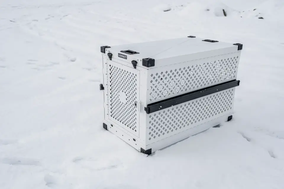 A hard-sided plastic dog crate with a metal wire door, used for travel