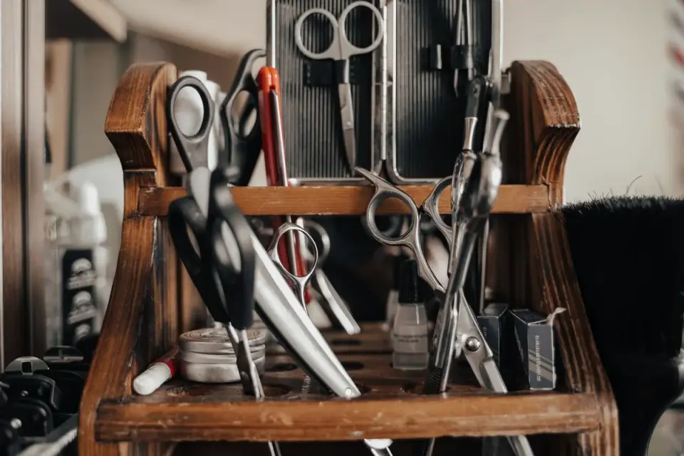 A metal comb, slicker brush, and nail clipper arranged on a table as a beginner grooming kit