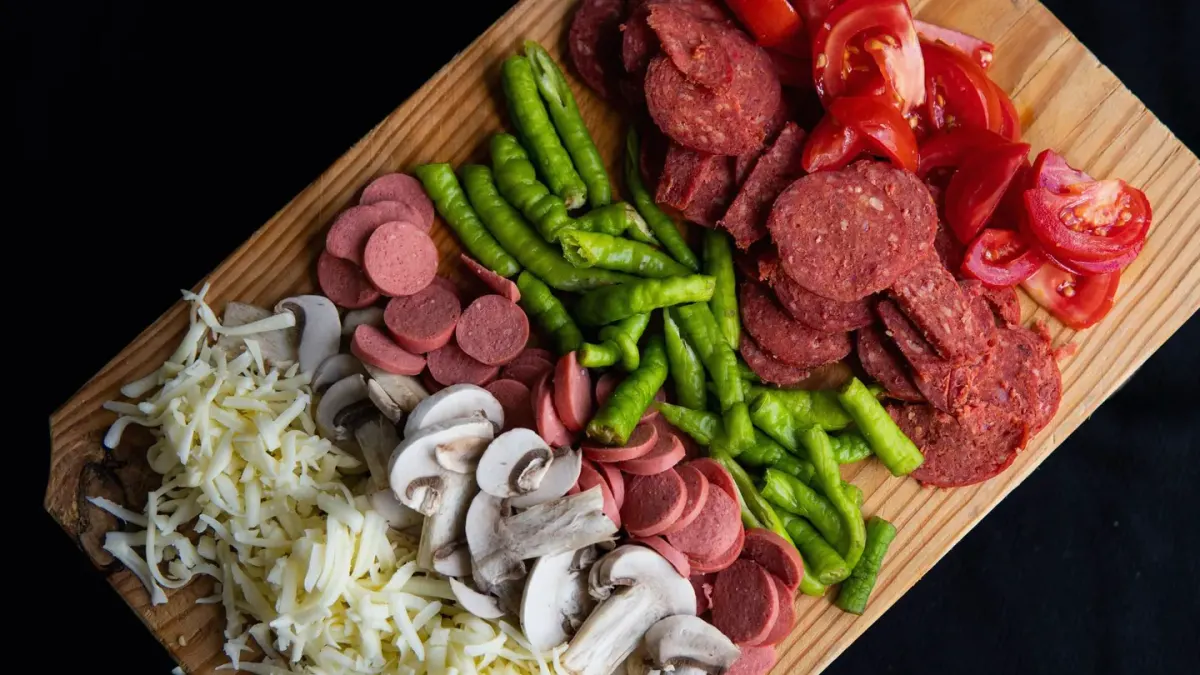 A portioned raw dog food meal with muscle meat, organ, and chopped vegetables on a cutting board