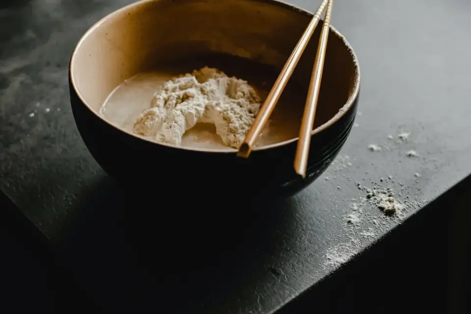 A scoop of supplement powder being stirred into a dog&#x27;s food bowl