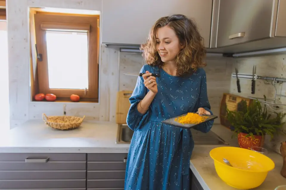 A senior dog eating from a stainless bowl in a home kitchen
