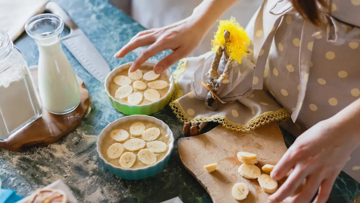 A small dog sniffing at a few banana slices on a kitchen counter