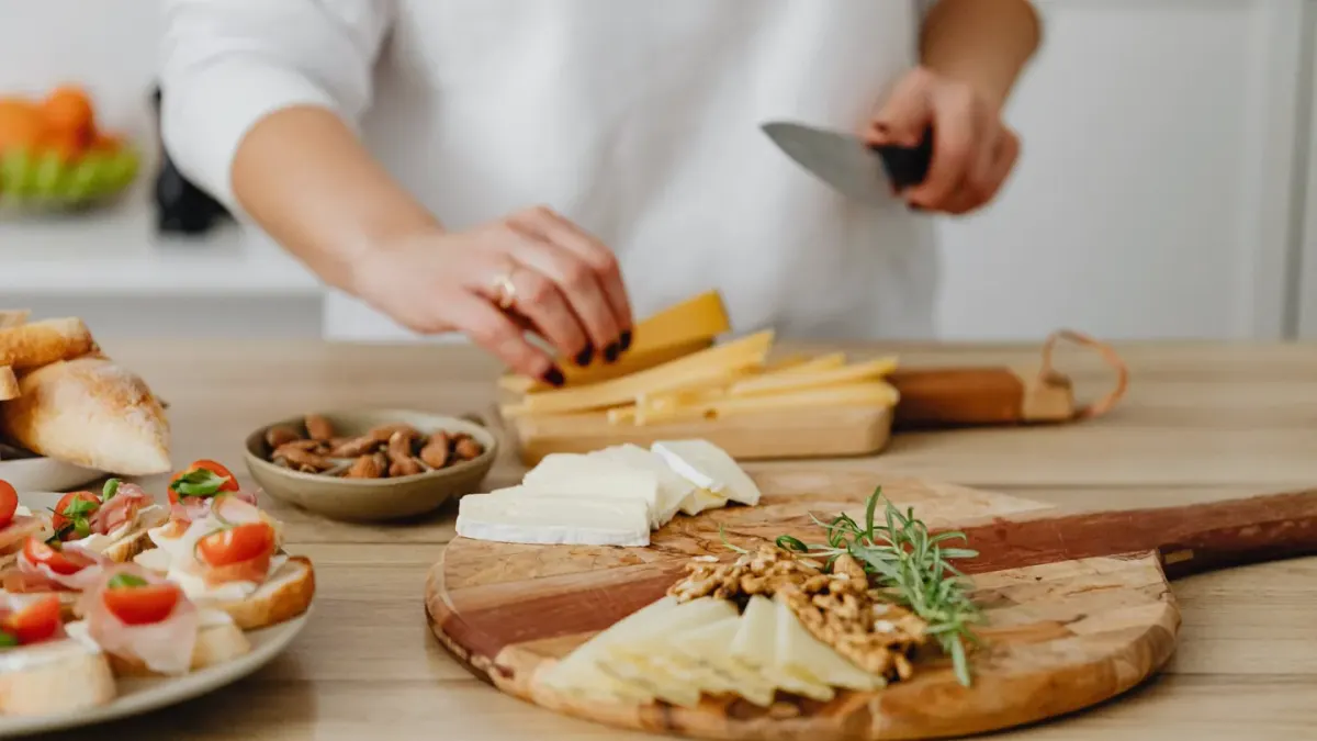 A small dog sniffing a cube of cheese sitting on a wooden cutting board