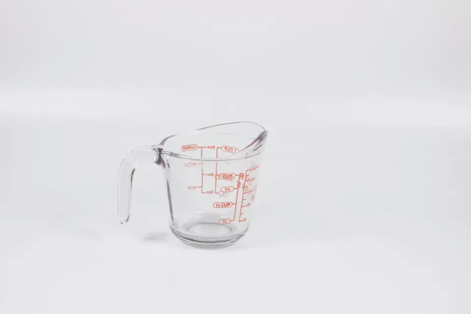 Dry kibble being poured into a measuring cup for portioning