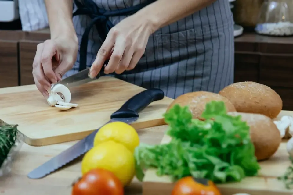 Sliced cremini mushrooms on a wooden cutting board